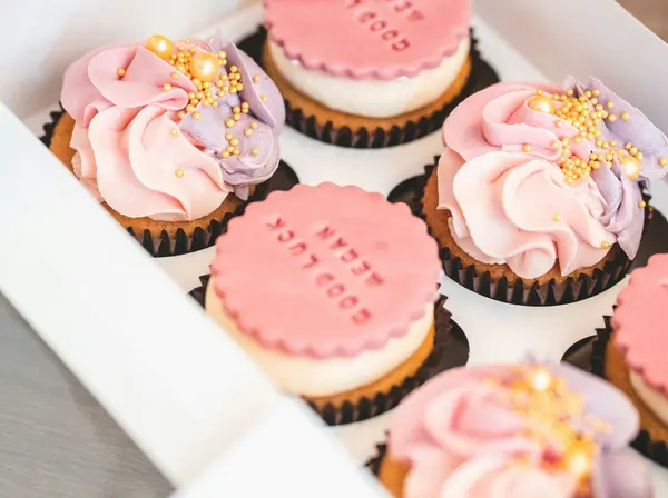 A box of cupcakes with pink frosting