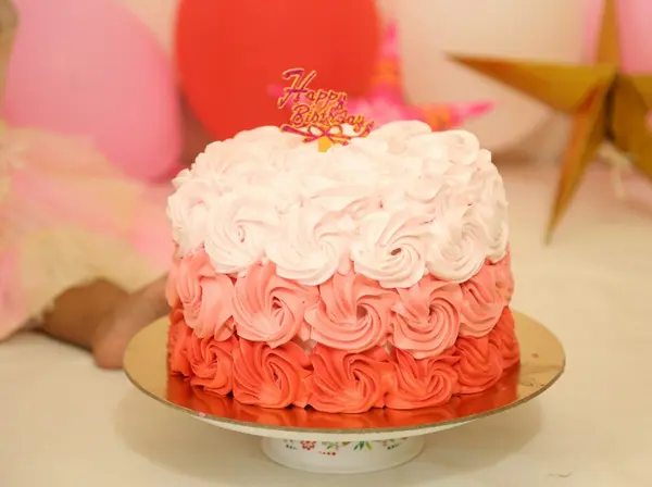 A pink rosette birthday cake with a gold topper